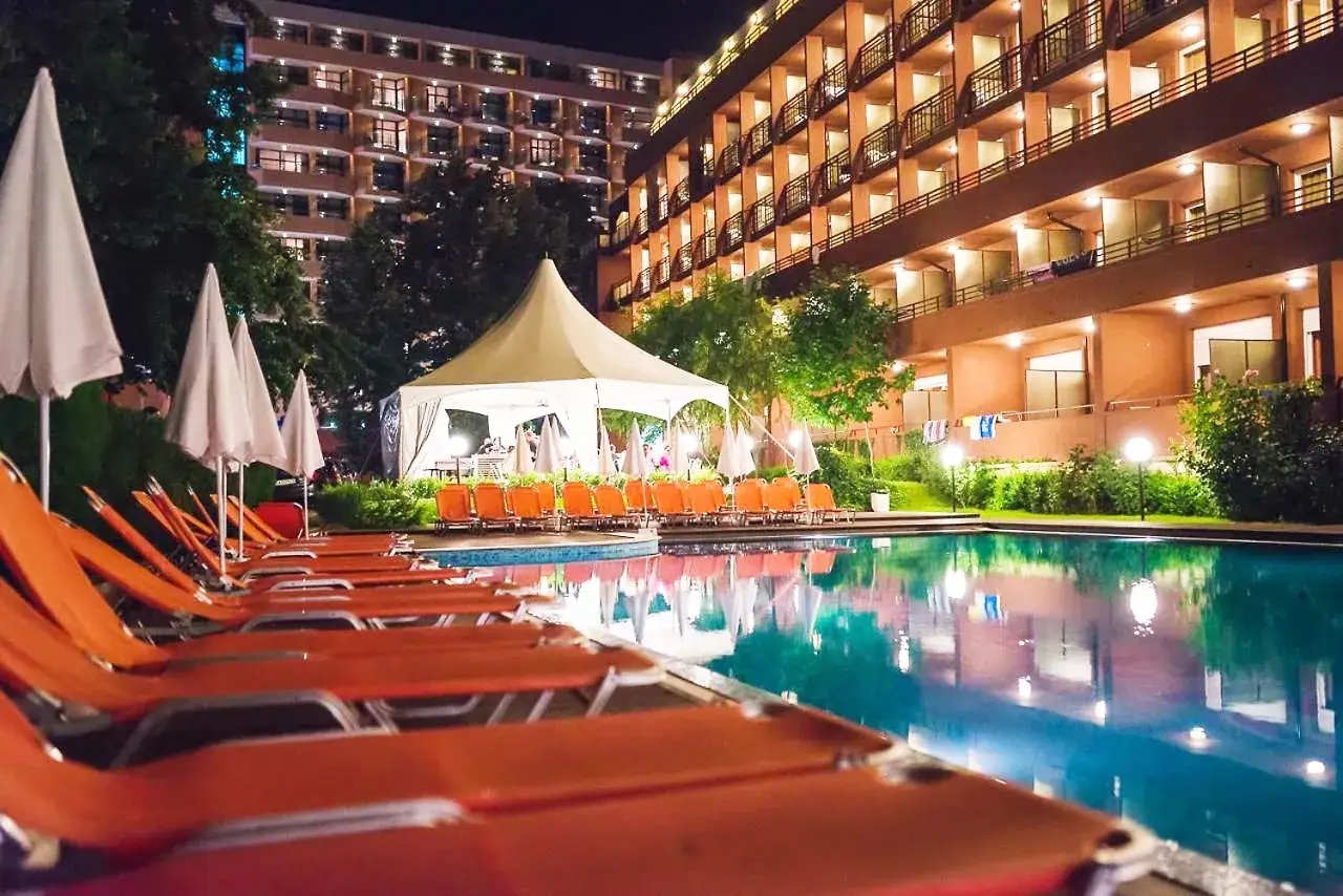 Pomarańczowe leżaki przy basenie, hotelowa gwiazda, namiot i parasole tworzą wakacyjny klimat.