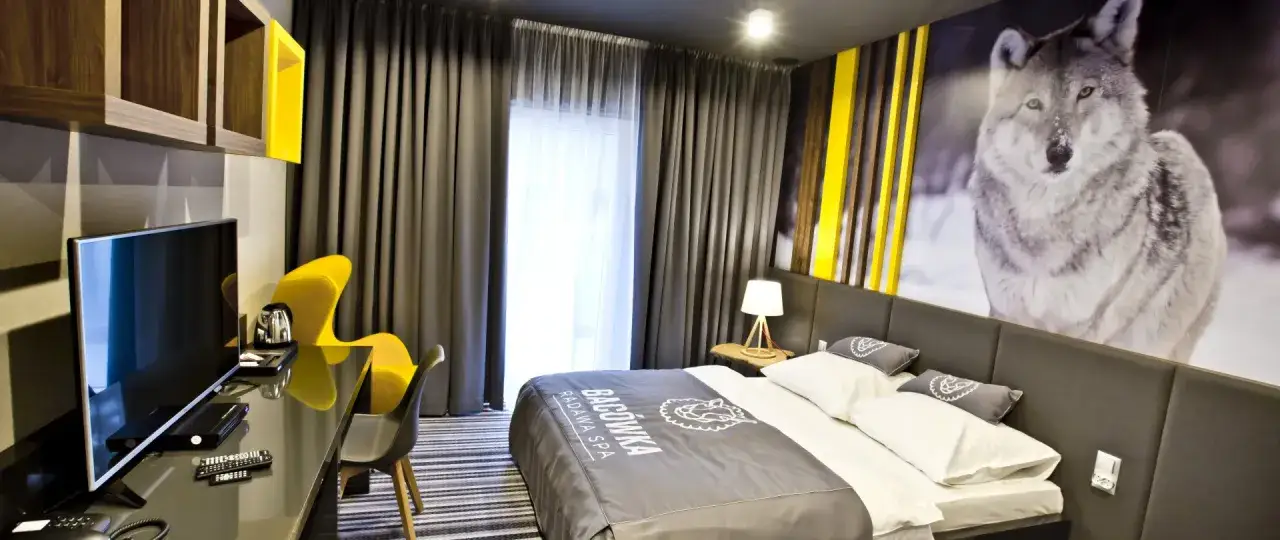 Pokój hotelowy 4-gwiazdkowy z motywem wilka na ścianie, żółtym fotelem i nowoczesnym wystrojem.