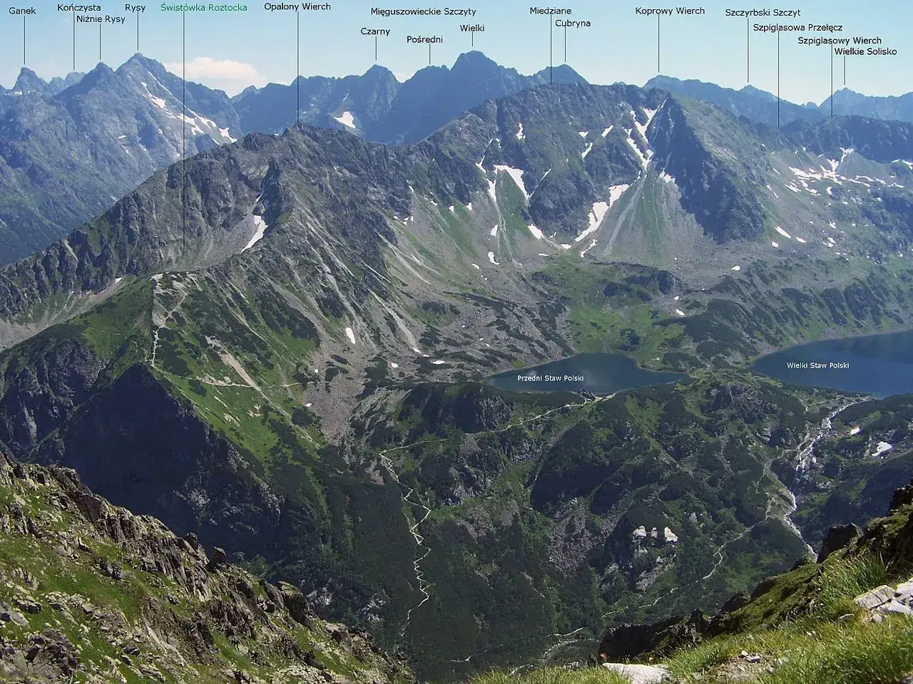 Widok na Tatry z Rysami, najwyższym szczytem Tatr, w oddali. W dole jeziora Wielki i Przedni Staw Polski.